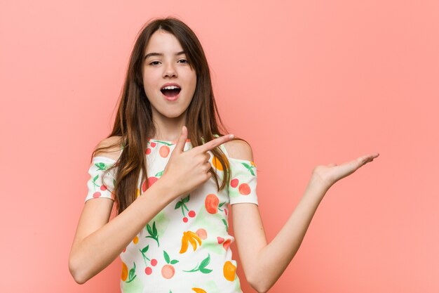 Garota vestindo uma roupa de verão contra uma parede vermelha animado, segurando um espaço de cópia na palma da mão.