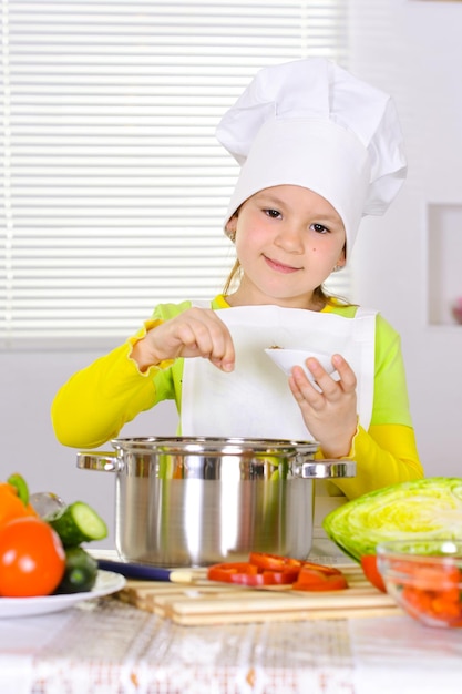 Garota vestindo uniforme de chef cozinhando na cozinha