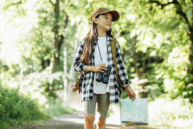 Garota viajante na floresta com binóculo e mapa