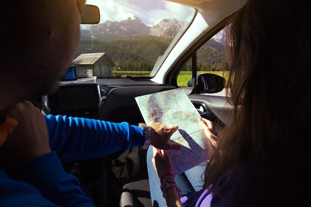 Garota viajante sentada no carro, olhando o mapa. Dolomitas, Itália.