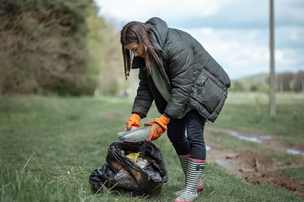 Garota voluntária coleta lixo na floresta, cuida do meio ambiente.