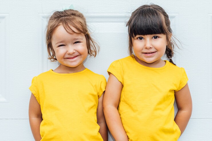 Garotas adoráveis vestindo uma camisa amarela encostadas em um fundo branco