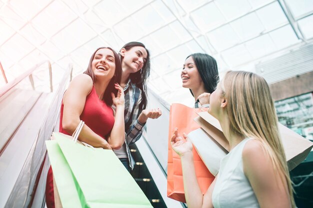 Garotas bonitas e felizes estão na escada rolante rindo