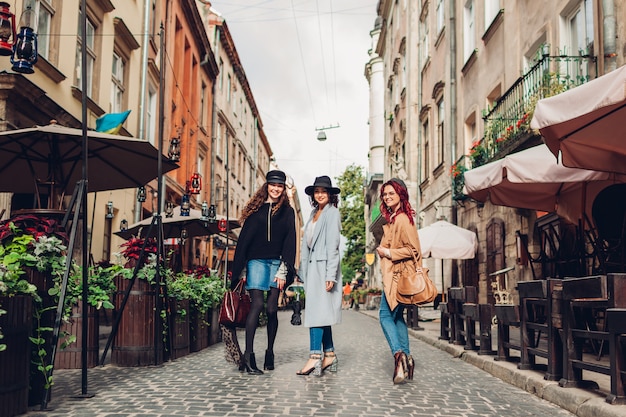 Garotas conversando e se divertindo. Tiro ao ar livre de três jovens mulheres andando na rua da cidade.