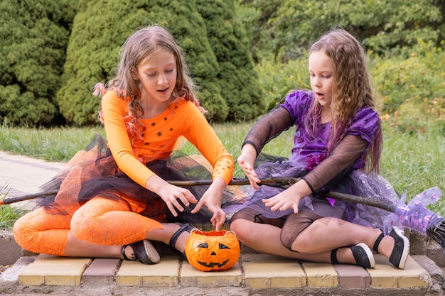 Garotas de Halloween com fantasias de bruxas conjurando uma abóbora