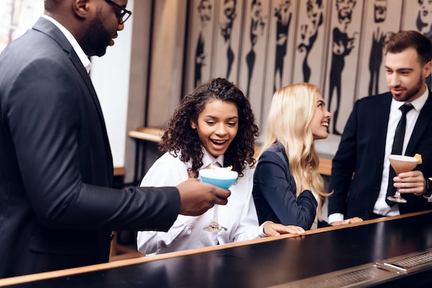 Garotas e garotos se comunicam em um bar.