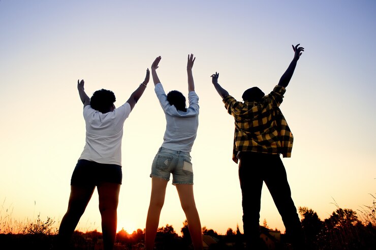 Foto garotas felizes, de diferentes nacionalidades, vistas de trás, ao pôr do sol no verão.