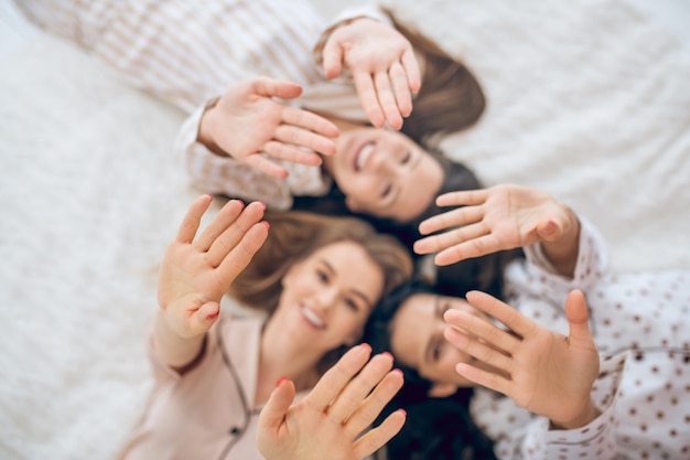 Garotas felizes. Três garotas deitadas na cama sorrindo e parecendo felizes