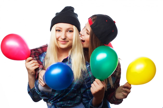 Garotas hipster sorrindo e segurando balões coloridos