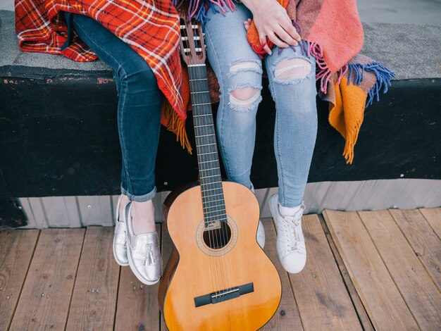 Garotas irreconhecíveis descansam na festa no telhado com o violão. Celebração e tempo de lazer do adolescente abrem espaço, estudando música, compartilhando o tempo em um ambiente alegre