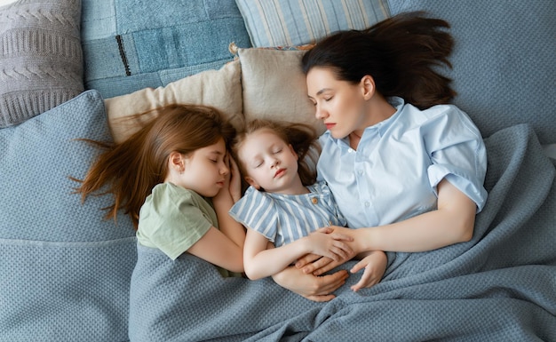 Garotas legais e sua mãe estão dormindo na cama. Bom tempo em casa.