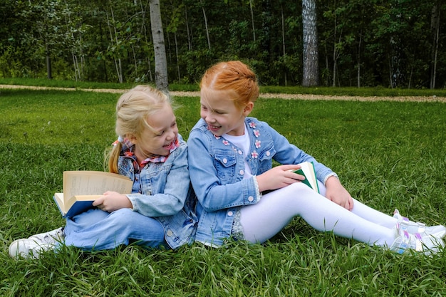 Foto garotas lendo um livro sobre grama verde