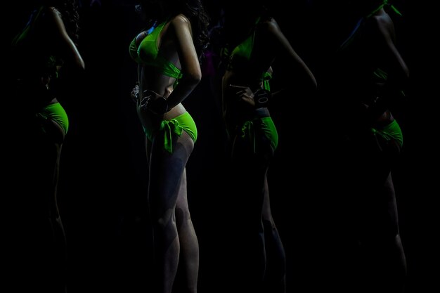 Garotas magras sensuais postando na luz do dard na fileira com biquíni neon