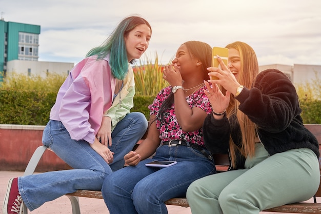 Garotas multiétnicas se divertindo assistindo algo no smartphone de uma amiga