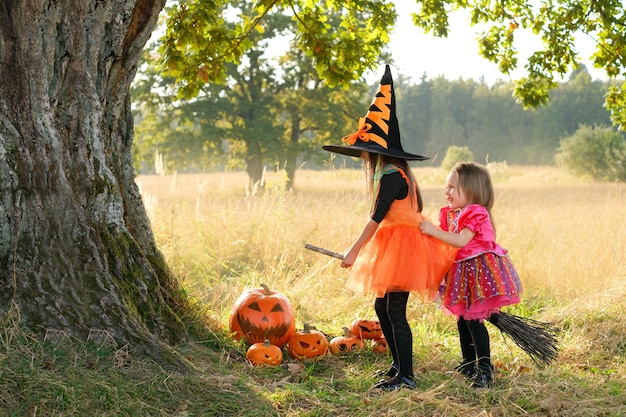 Garotas rindo alegremente sentadas em uma vassoura no Halloween