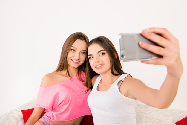 Garotas sexy e atraentes de pijama fazendo selfie no quarto