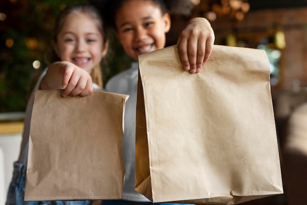 Garotas sorridentes de tiro médio segurando sacolas de papel