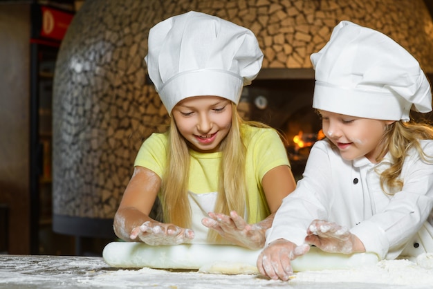 Garotas vestidas de cozinheira fazendo massa