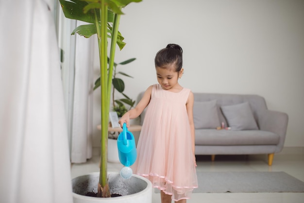 Garotinha ativa na pré-escola regando plantas com lata de água em casa