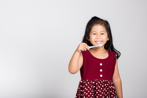 Garotinha bonitinha de 3 anos escovando os dentes e sorrindo