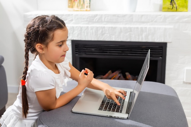 Garotinha criança estudante estudando aula online com laptop em casa, Novo normal. Coronavírus Covid-19. Distanciamento social, educação em casa.