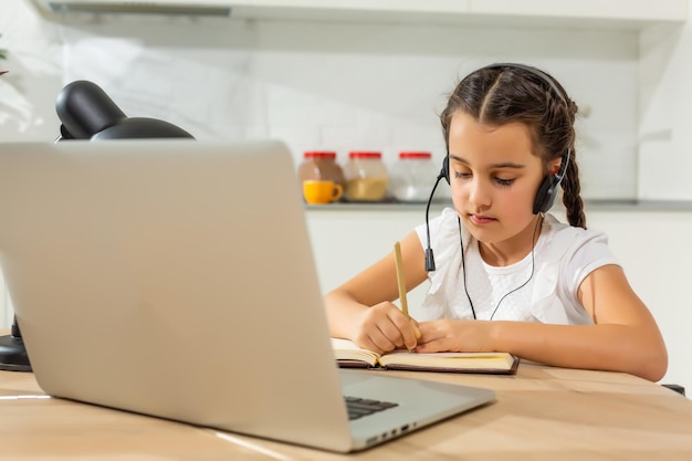 Garotinha criança estudante estudando aula online com laptop em casa, Novo normal. Coronavírus Covid-19. Distanciamento social, educação em casa.