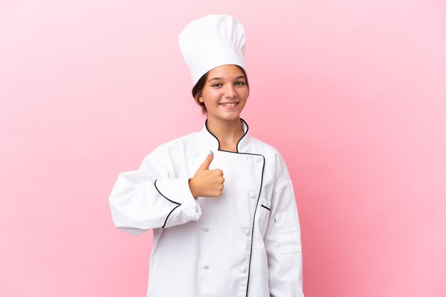 Garotinha de chef caucasiana isolada em fundo rosa, dando um polegar para cima gesto