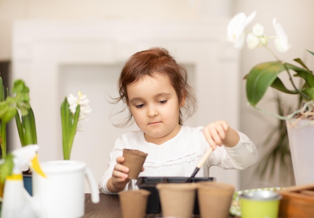 Garotinha de jardinagem doméstica ajudando a cuidar de plantas em casa ambiente verde em casa