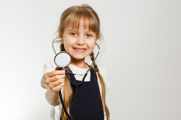 garotinha estuda medicina com estetoscópio, isolado no branco
