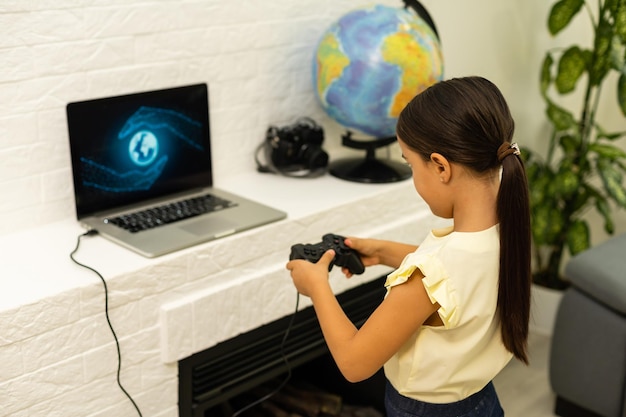 garotinha jogando com o laptop e o controle do joystick