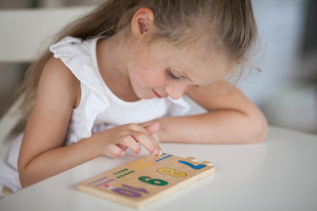 Garotinha linda criança em idade pré-escolar jogando jogos educativos com madeira