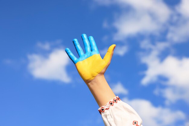 Garotinha pintada à mão nas cores da bandeira ucraniana contra o céu azul fechado Conceito de amor da Ucrânia