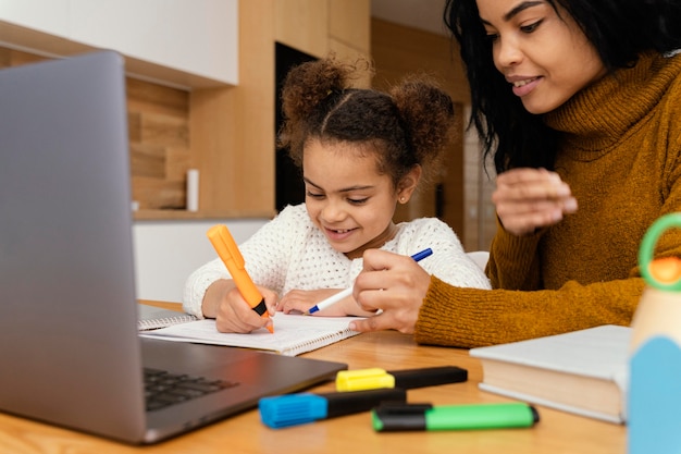 Garotinha sorridente e irmã mais velha em casa durante a escola online