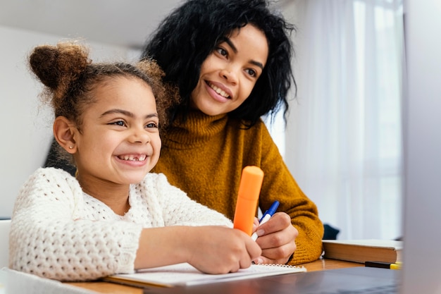 Foto garotinha sorridente em casa durante a escola online com a irmã mais velha