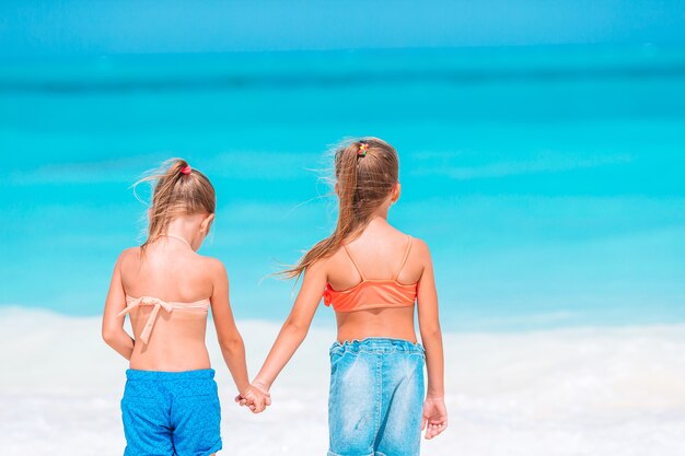 Garotinhas engraçadas felizes se divertem muito na praia tropical brincando juntas.