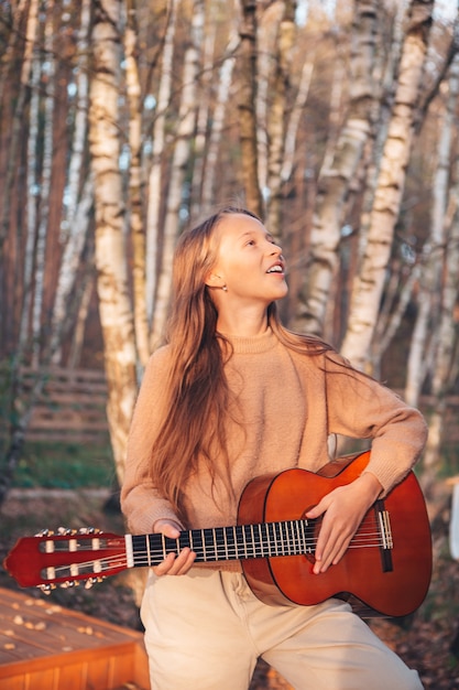 Garotinhas lindas tocando violão em um dia de outono ao ar livre