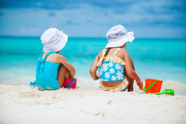 Garotinhas se divertindo em uma praia tropical brincando juntas e fazendo castelo de areia
