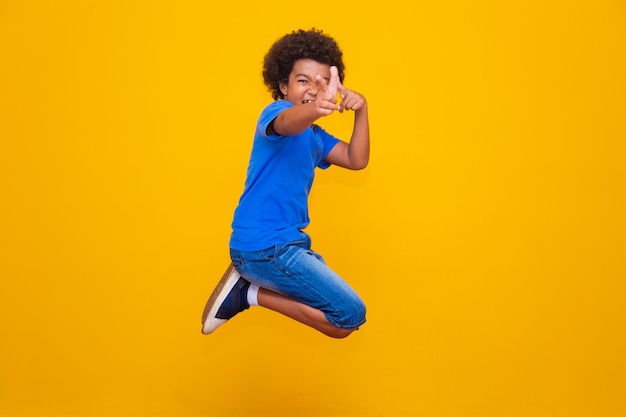 Garotinho afro, pulando sobre fundo amarelo.