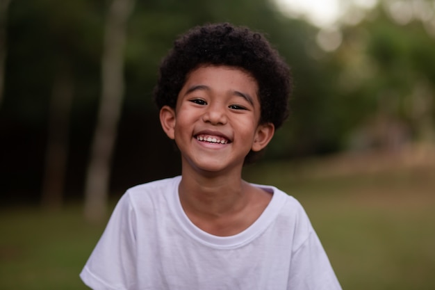 Foto garotinho afro sorrindo para a câmera no parque