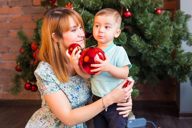 Garotinho ajudando sua mãe a decorar a árvore de natal.