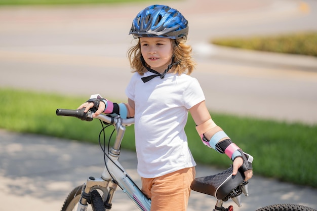 Garotinho andando de bicicleta no parque de verão crianças aprendendo a dirigir uma bicicleta em uma calçada fora