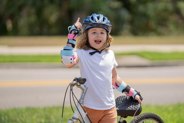 Garotinho andando de bicicleta no parque de verão crianças aprendendo a dirigir uma bicicleta em uma garagem