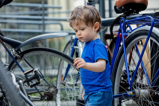 Garotinho brinca com entusiasmo com bicicletas grandes em um estacionamento de bicicletas da cidade