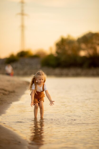 Garotinho brinca na margem arenosa do rio viagens de férias de verão Lazer infantil e familiar na natureza Rio do mar verão clima quente resfriamento praia jogos ao ar livre foco seletivo