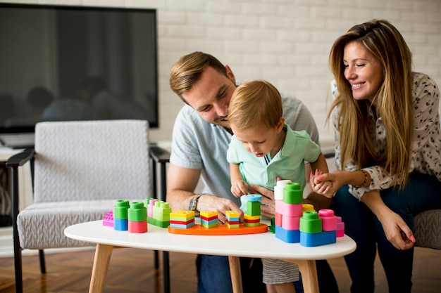 Garotinho brincando com brinquedos na sala de estar com pai e mãe