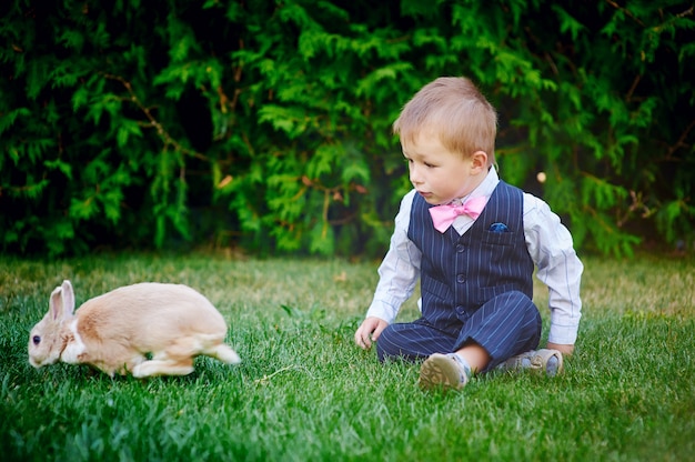 Garotinho brincando com um coelho no jardim de verão