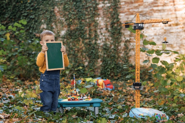 Garotinho brincando com uma grande construção amarela, brinquedo de guindaste, atividade criativa para crianças