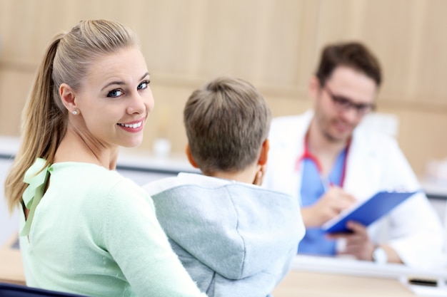 Garotinho com a mãe na clínica sendo examinado pelo pediatra