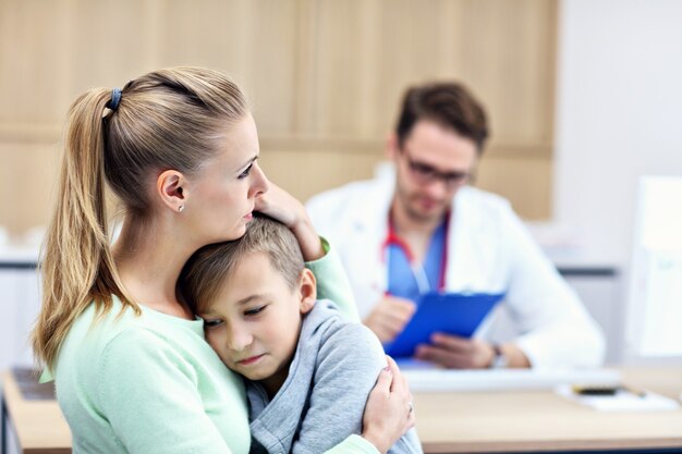 garotinho com a mãe na clínica sendo examinado pelo pediatra