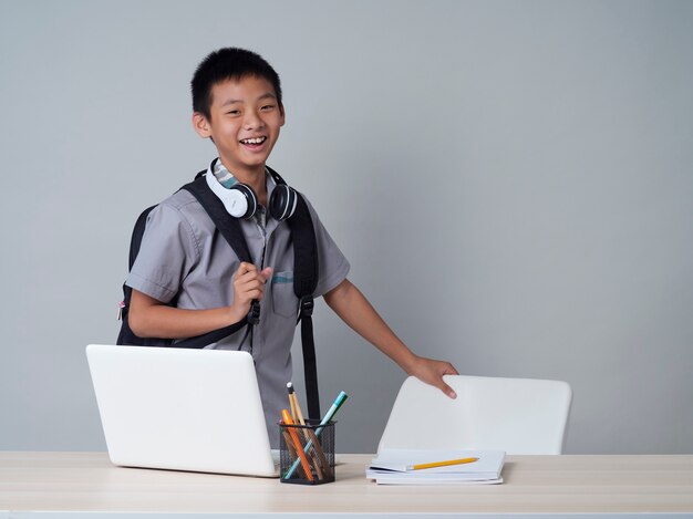 Garotinho com fones de ouvido, estudando on-line usando um laptop